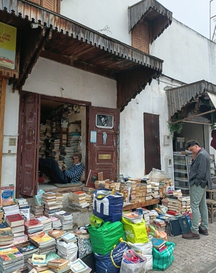 Alex Ripoll ante una librería de viejo con libros apilados en la calle